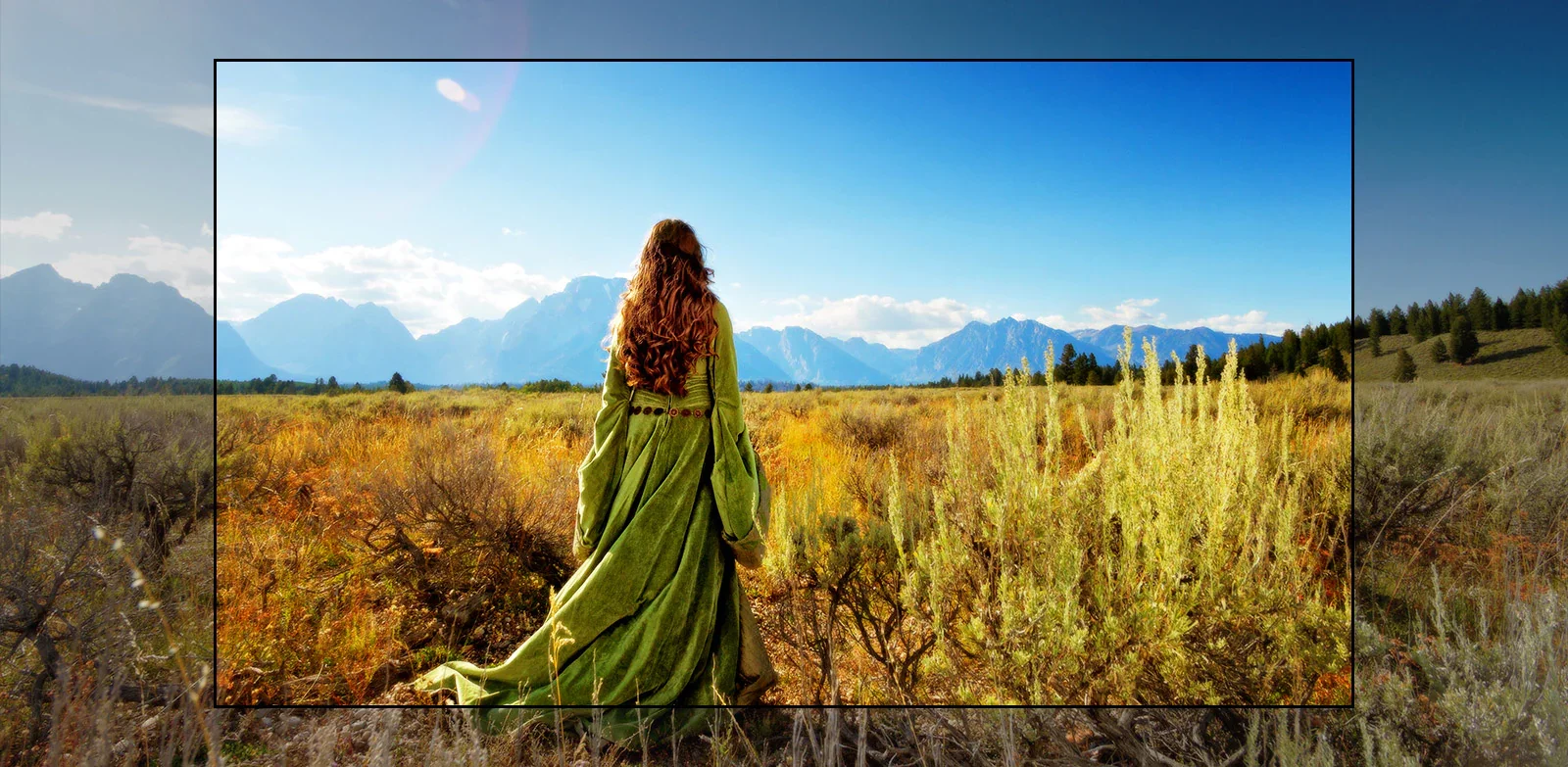 Uma tela de TV mostrando uma cena de filme de fantasia com uma mulher em pé nos campos e de frente para montanhas.